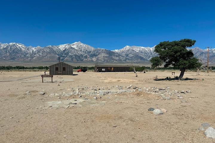 a lone building in a desert with mountains and blue sky in the background