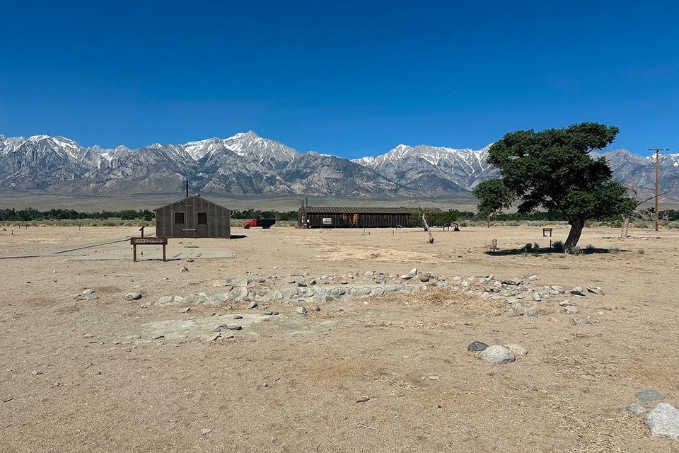 a lone building in a desert with mountains and blue sky in the background