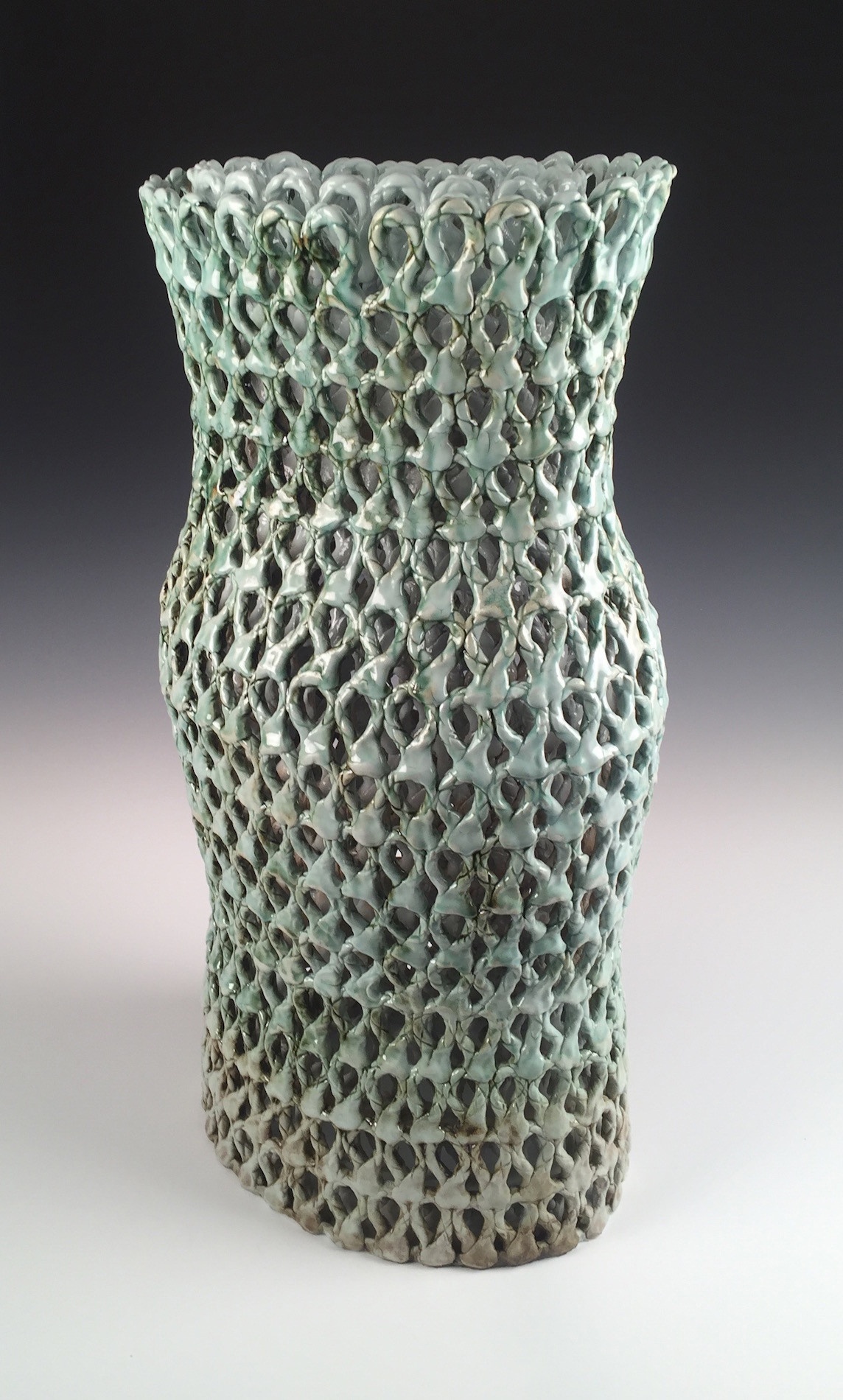 A tall, intricately looped/patterned and layered vessel in a light sage color.