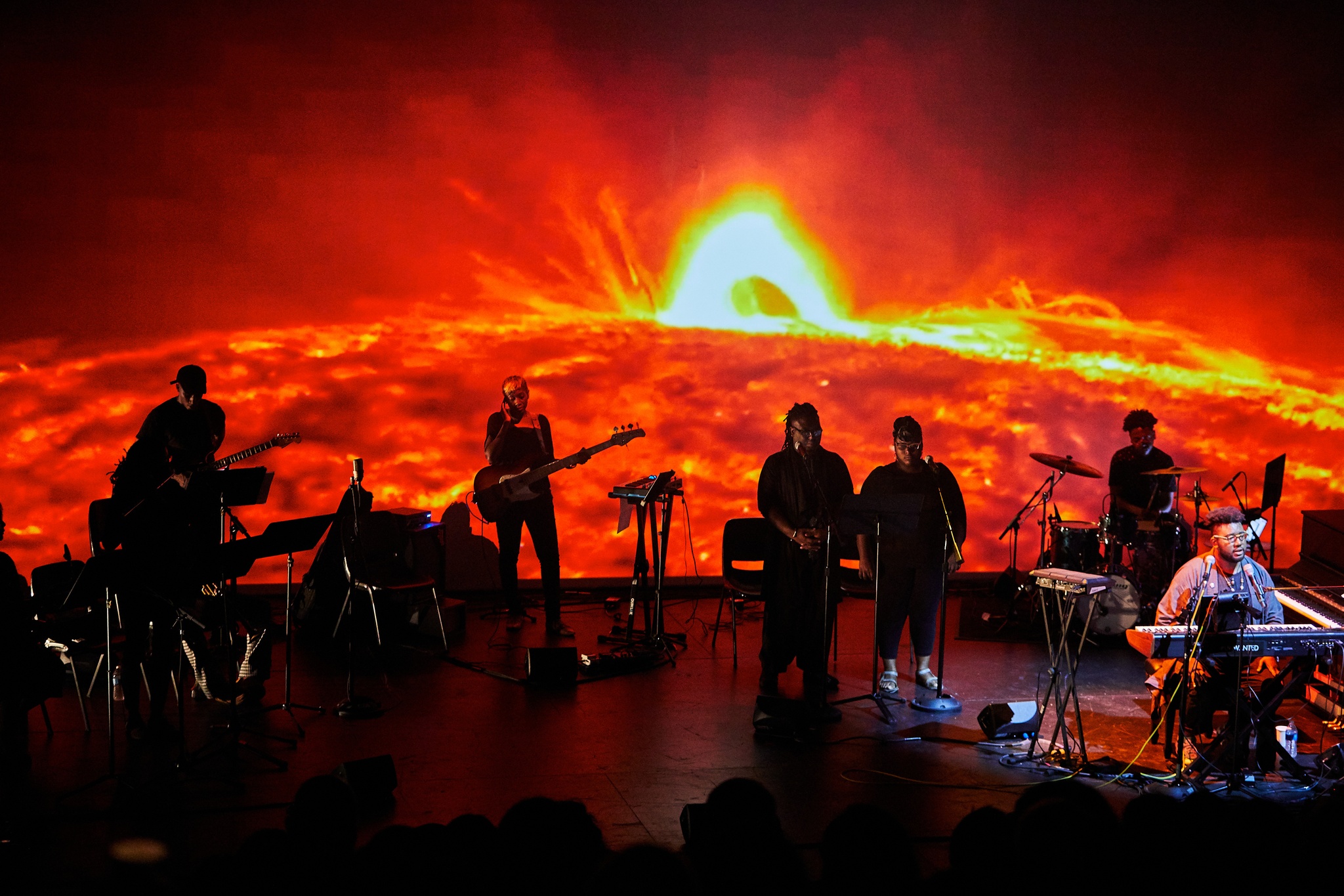 Band on stage performing in front of large screen of lava.