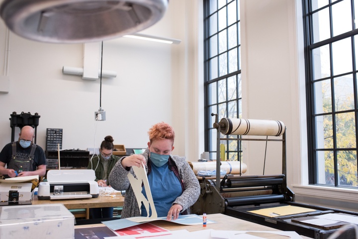 Several people work in a printmaking workshop.