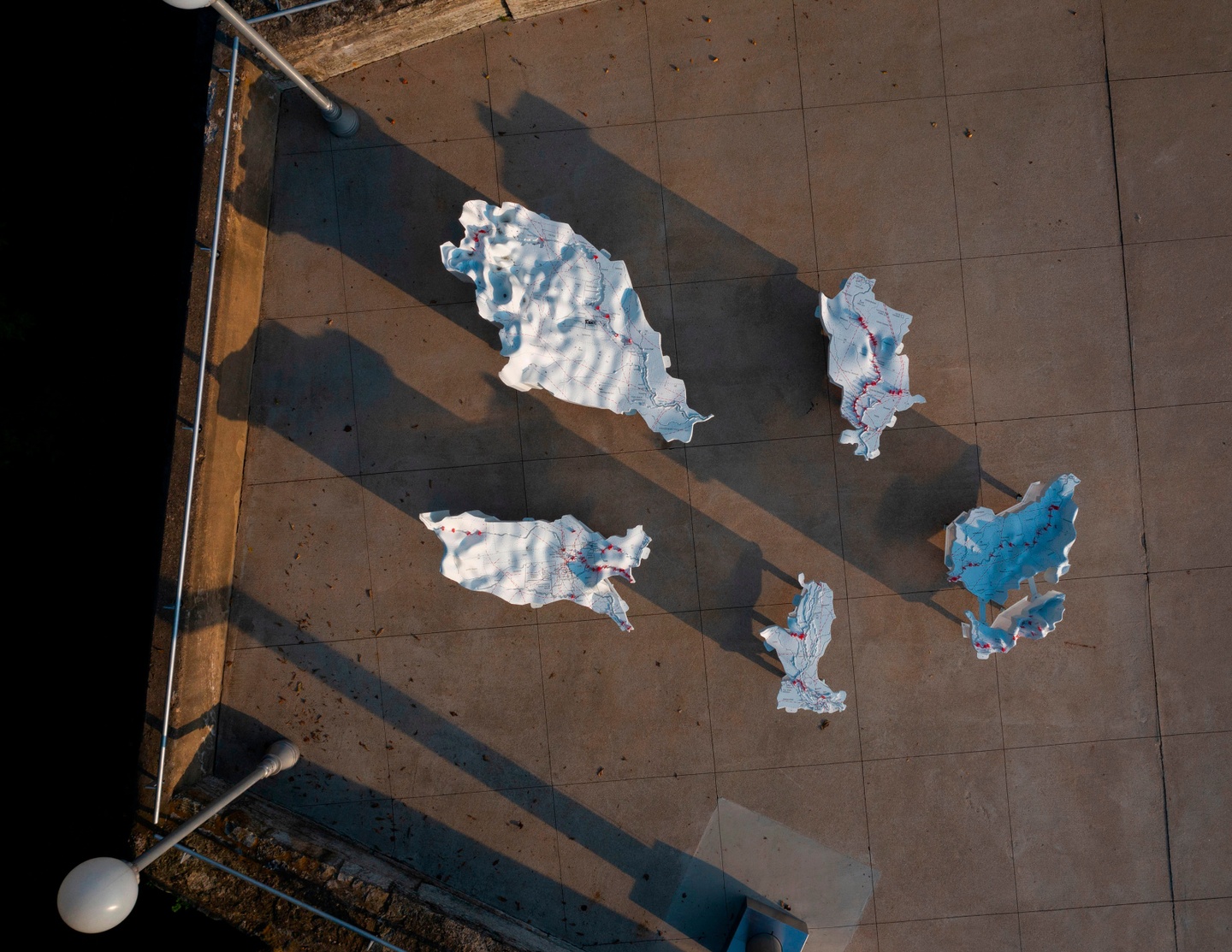 Aerial photo of five, undulating white architectural models with some red circles and lines.