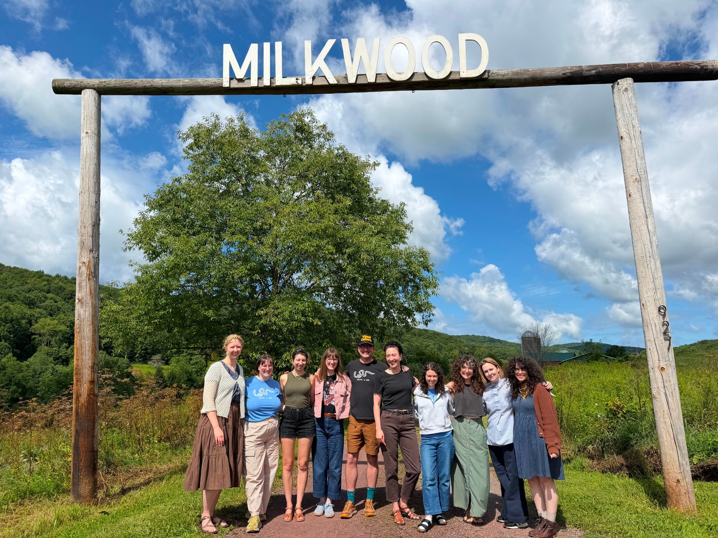 group photo of people under a wooden sign that say Milkwood