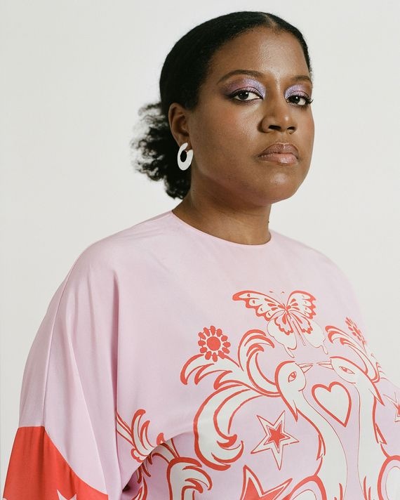 A photo of Stephanie Baptist with her hair pulled back and wearing a pale pink shirt with a design depicting birds and a butterfly. 