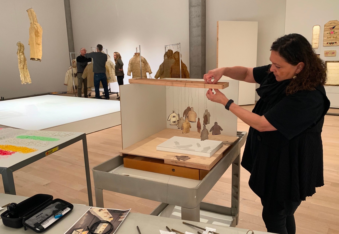 Artist Sonya Kelliher-Combs wearing black, standing over a a table putting together a display of her art in a gallery