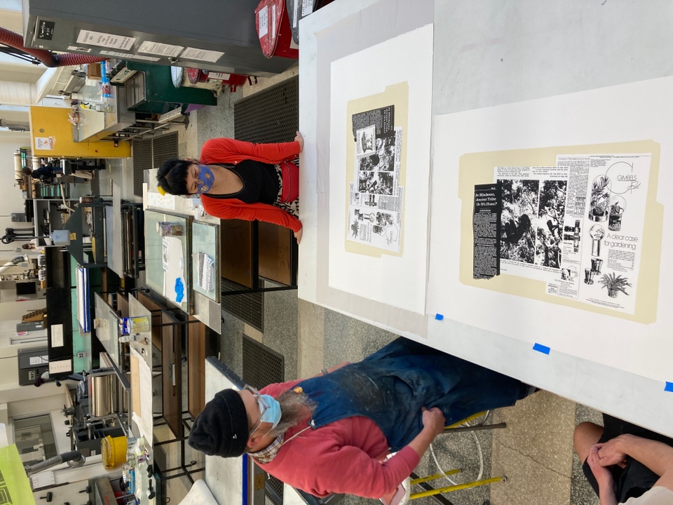 Looking down at prints on press while printer Tom Reed and artist Stephanie Syjuco study the prints.