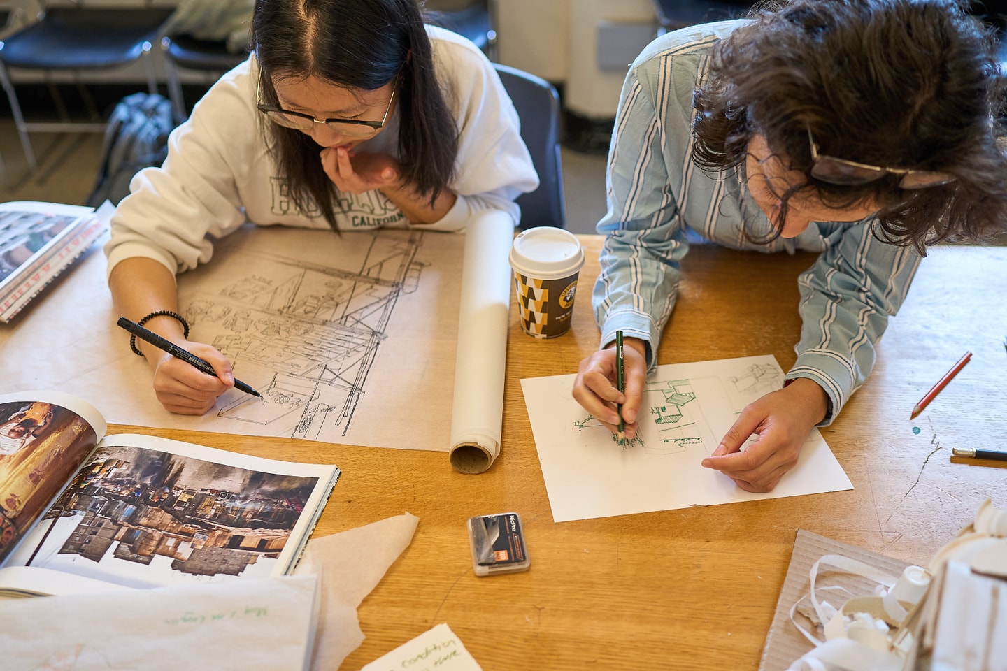 Student drawing by hand with photographic books nearby