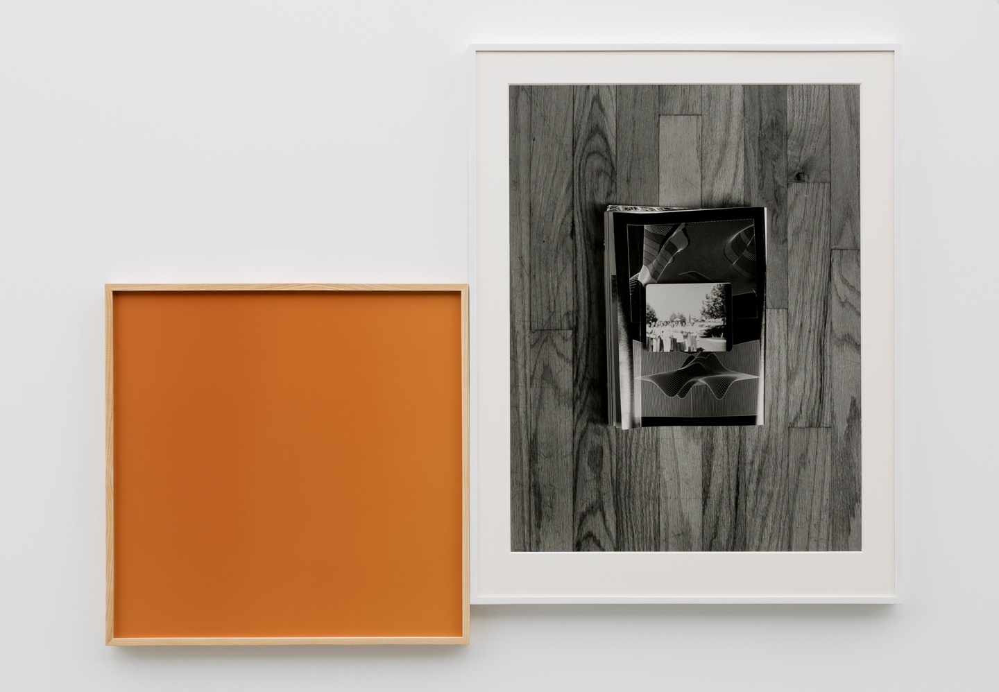 A framed orange square next to a framed black-and-white image of a photo on a wood panel