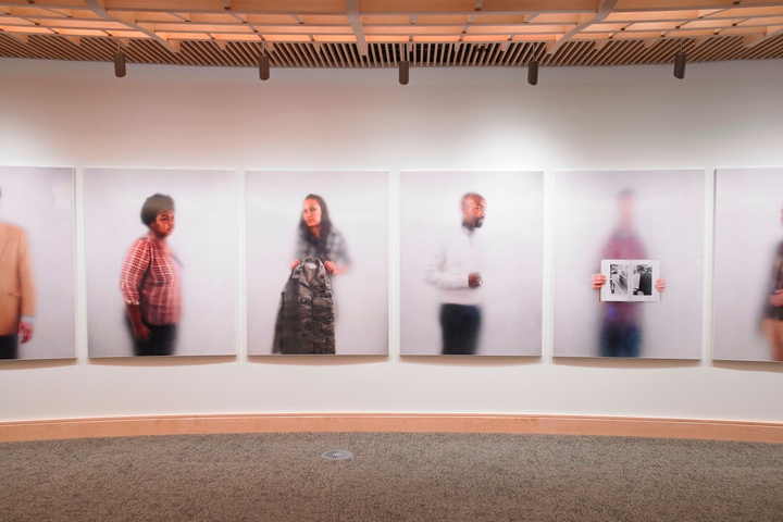 Artwork installation on a rounded wall, featuring a series of individual portraits translated into porcelain enamel panels.