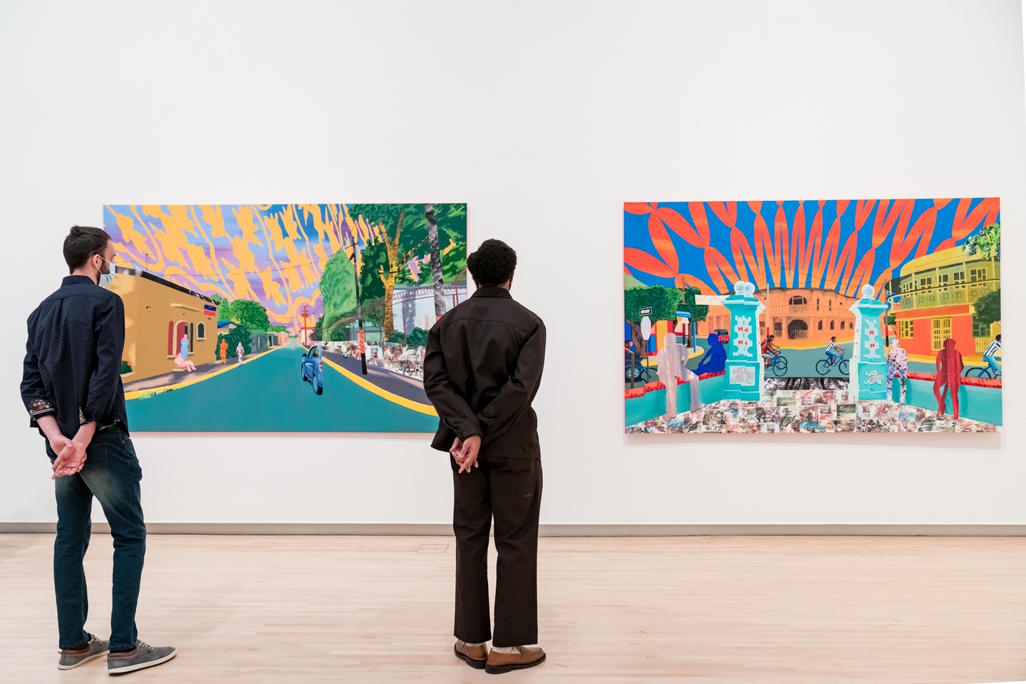 Two people looking at large colorful paintings