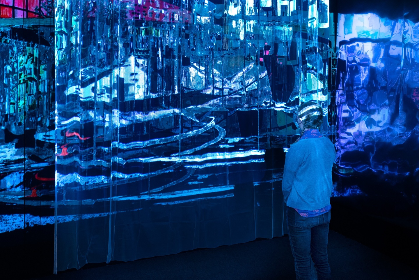 Light installation in a dark room with multiple layers of reflection and semi-transparent surfaces. The projections vaguely resemble stained glass and architecture.