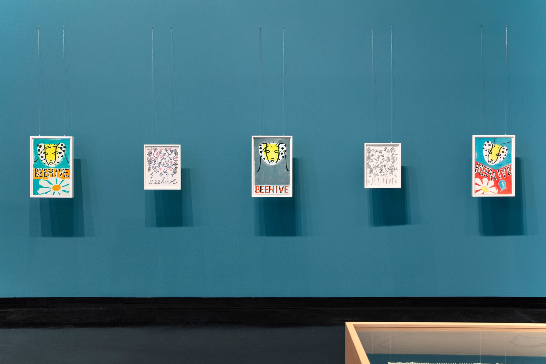 Framed drawings by Frank Moore hanging against a blue wall