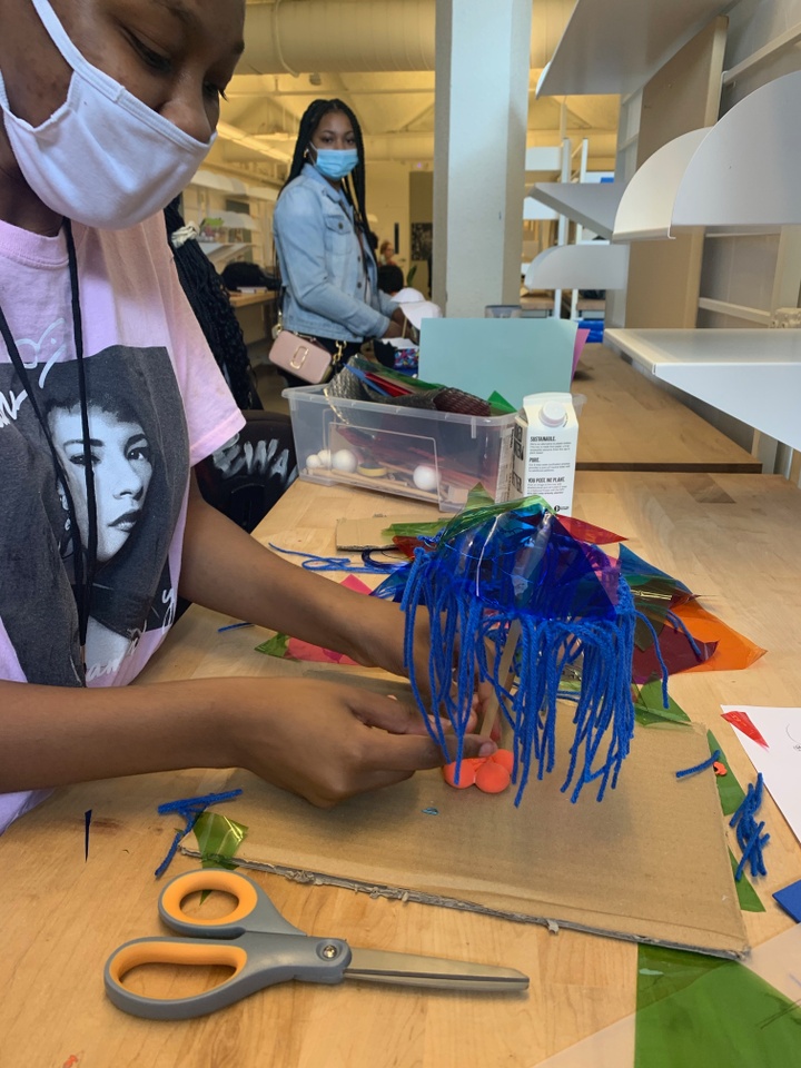 A student works on a model using cardboard and yarn.