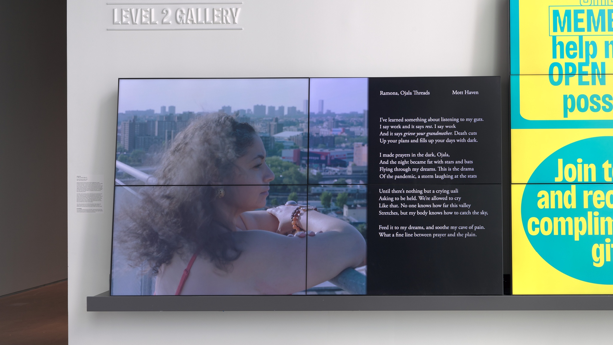 A video screen depicting a woman looking out on a neighborhood from a balcony with the text of a poem to the right of the frame.
