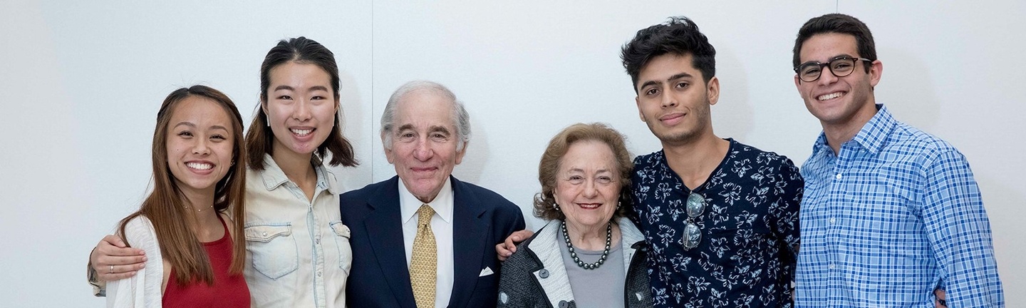 Four young adults and two older adults pose for a group photo.