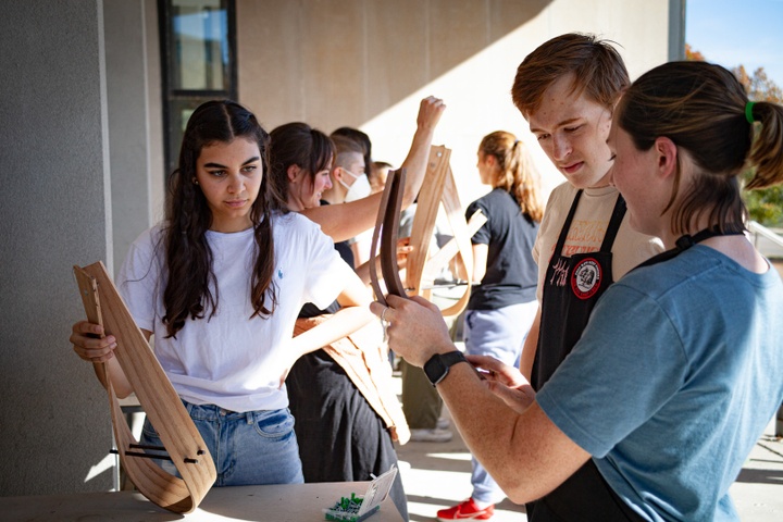 Students look on as a student assistant demonstrates steam bending