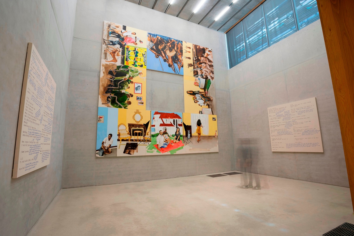 Museum installation featuring a large-scale, 11-panel work, configured as a square with a hole in the middle, featuring various, brightly painted scenes of people. Single artworks with cream-colored backgrounds and text are hung on the walls to the left and right.