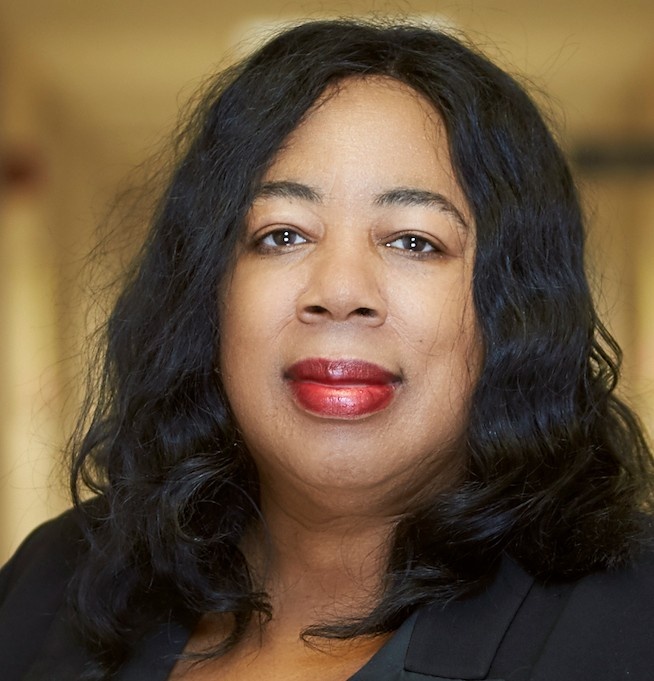 A portrait photo of Harriet Washington with black hair falling beneath her shoulders and wearing red lipstick