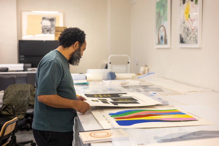artist William Villalongo standing in a studio looking at prints on the table