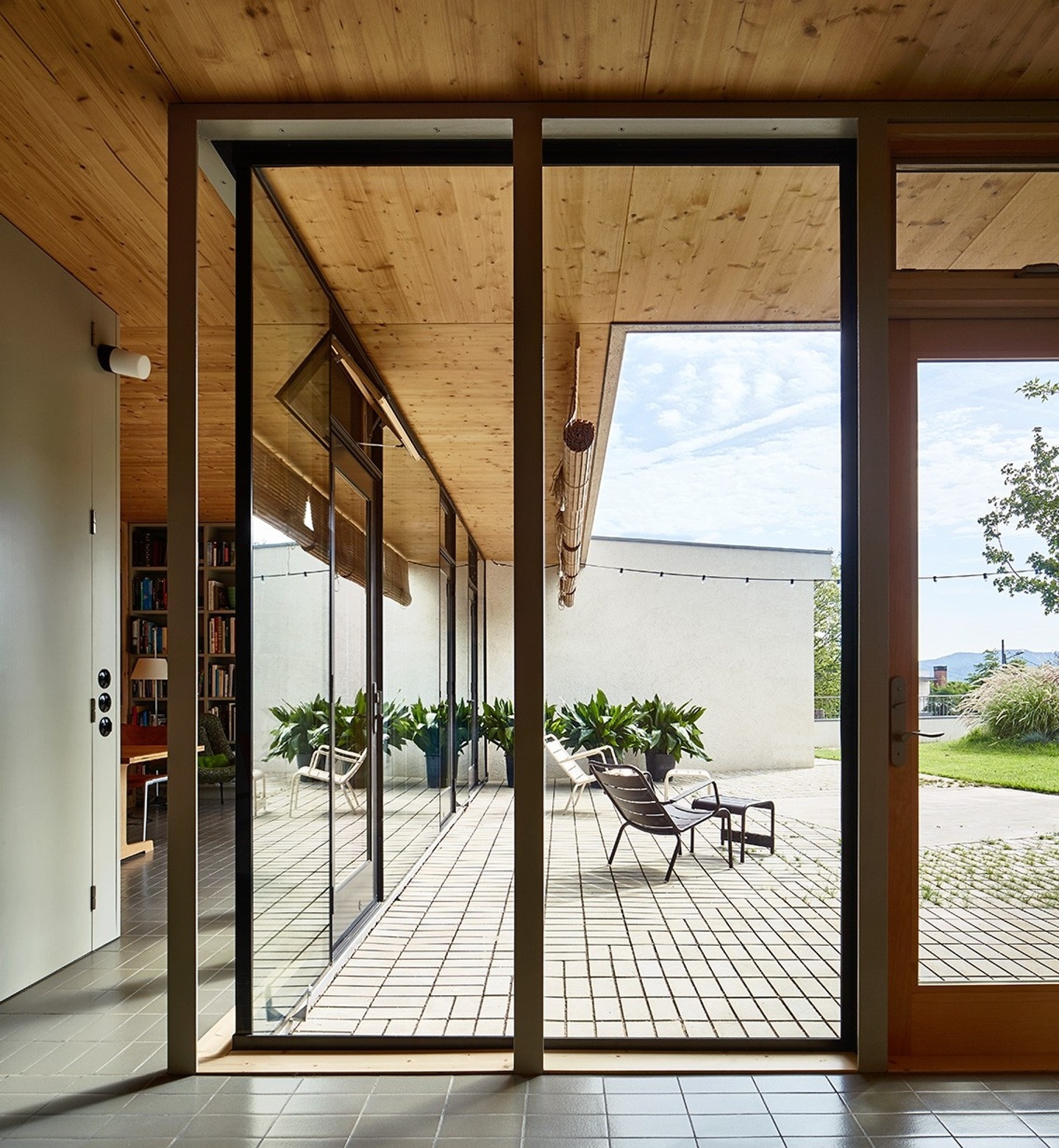 View from the inside of a centre. There are floor to ceiling windows and outdoor patio chairs are seen through the windows