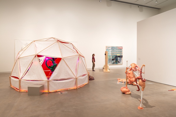 Overview shot of a gallery space containing a geodesic tent seen from the back.