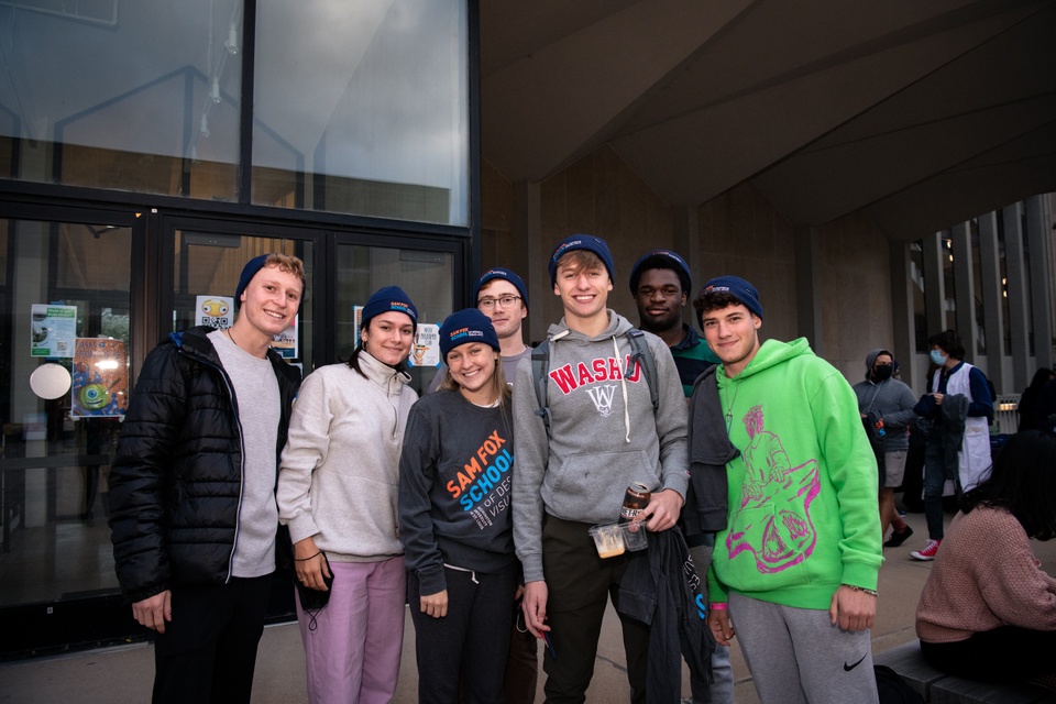 Photo of students in front of Steinberg Hall, some wearing Sam Fox School knit caps and shirts.