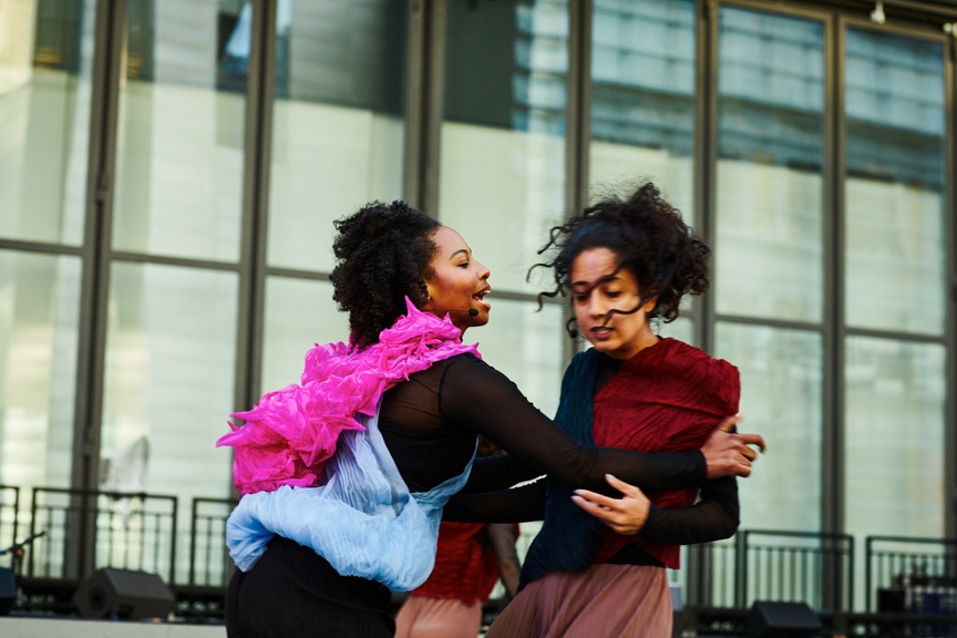 Two dancers in motion on an outdoor stage.