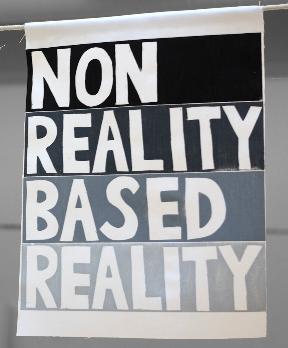 A grayscale woodcut image with four hand drawn words, one on each line, saying "non reality based reality."