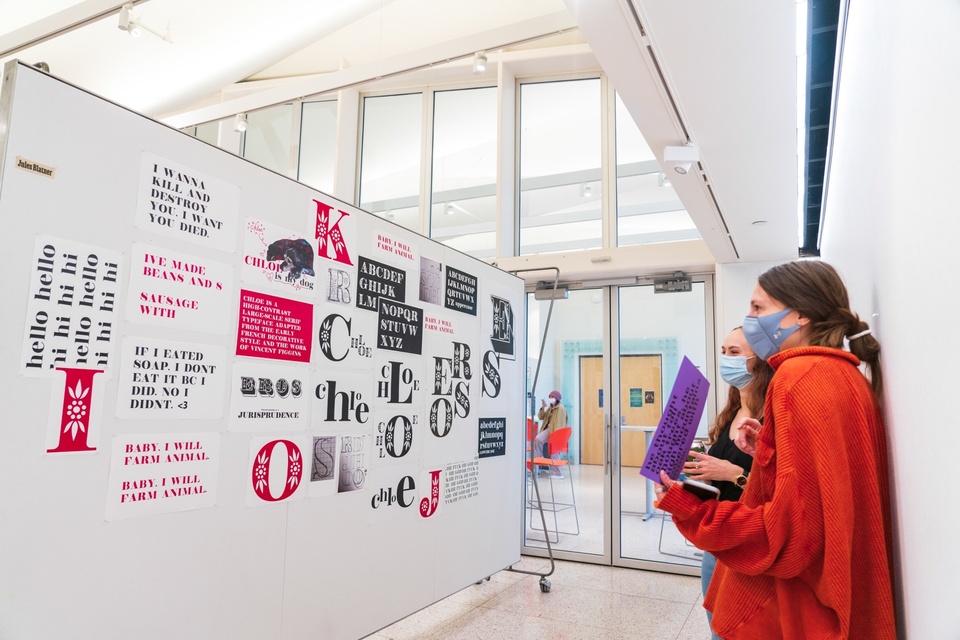 Students look at a wall of type samples of a high-contrast modern serif with embellished capitals.