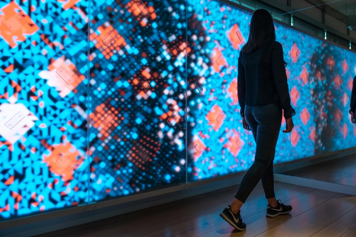 Young woman walking past wall displaying blurred graphics that react to her motion