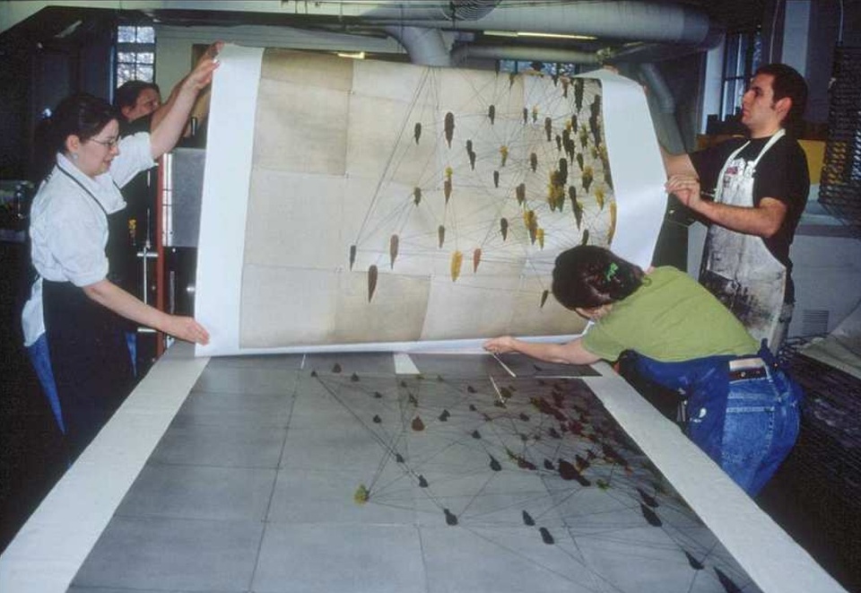 Four students lift a large print off the bed of the press.