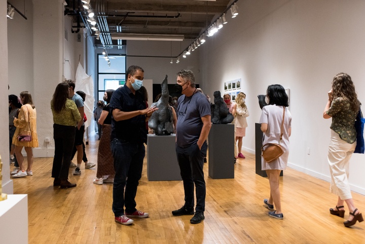 Two professors talk to each other in the middle of a gallery space