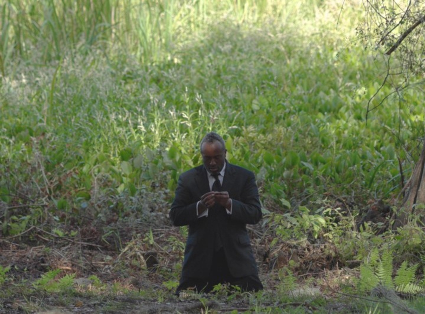 A man dressed in black kneels in front of a field