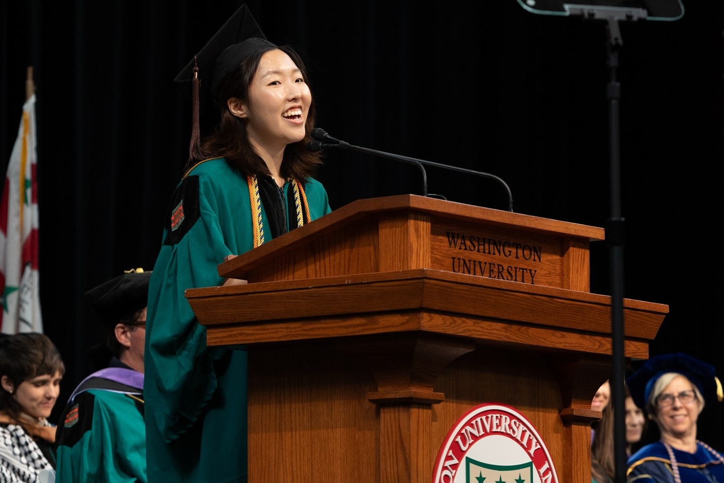 student in green regalia giving a speech at the Sam Fox School Recognition Ceremony