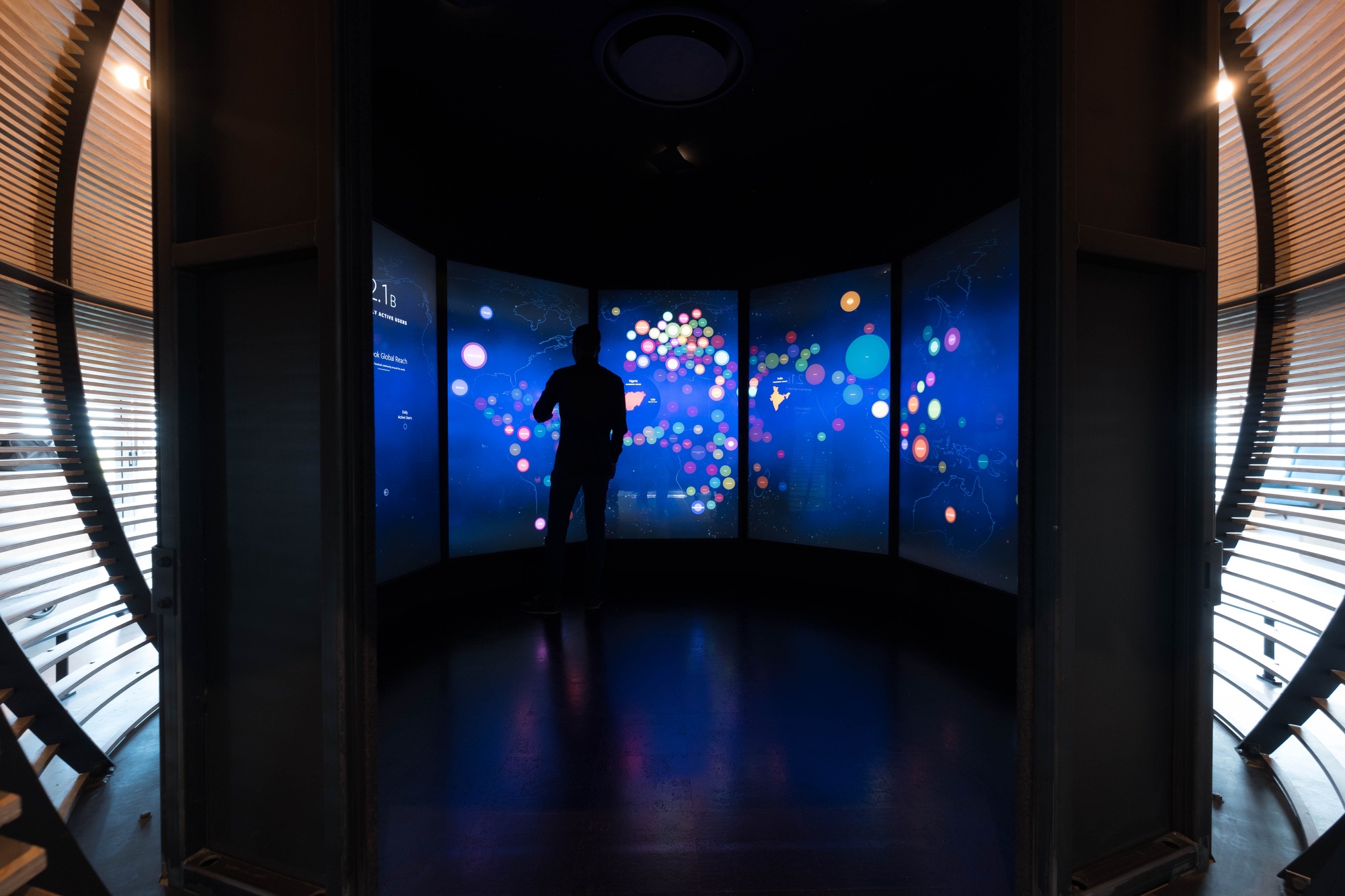 Image of domed installation, taken from the entrance, showing large screens that display data visualization on the inside