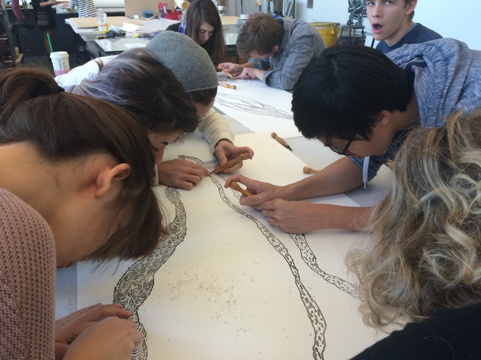 students working on the artist's project, carving a relief print