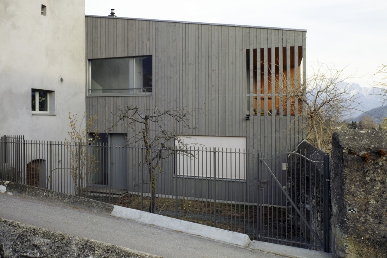 Concrete building with a grey wood-paneled facade on a hillside.