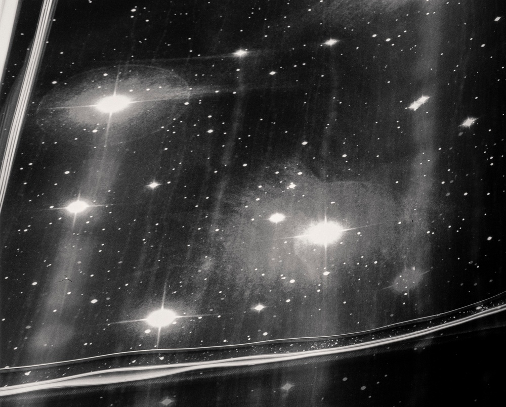 A black-and-white photograph showing a detail of a book corner with pages whose pages depict photographs of stars and orbs in the galaxy.