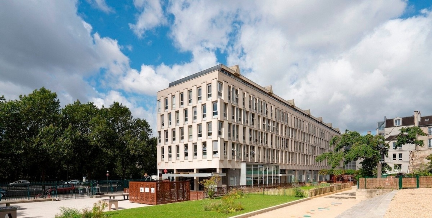 Exterior shot of building with green trees in background and blue sky with clouds