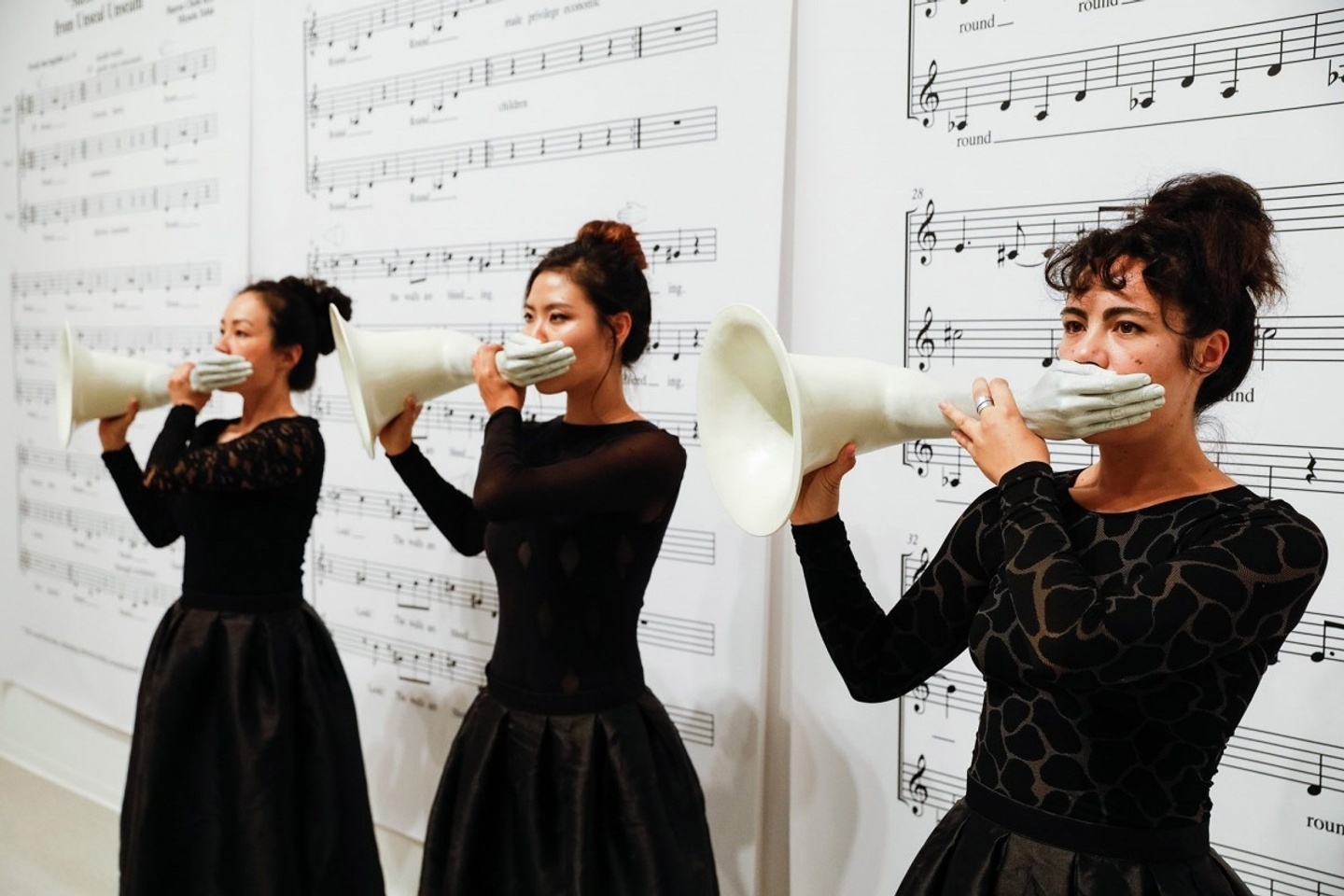 Musicians Micaela Tobin (right) and Sharon Chohi Kim (center) perform with Elana Mann’s “hands-up-don’t-shoot-horns” 