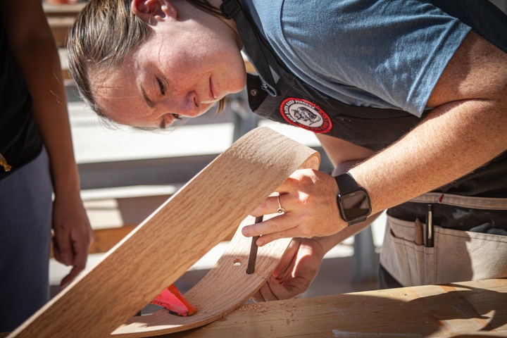 Closeup of a student inserting a rod across the steam bent wood