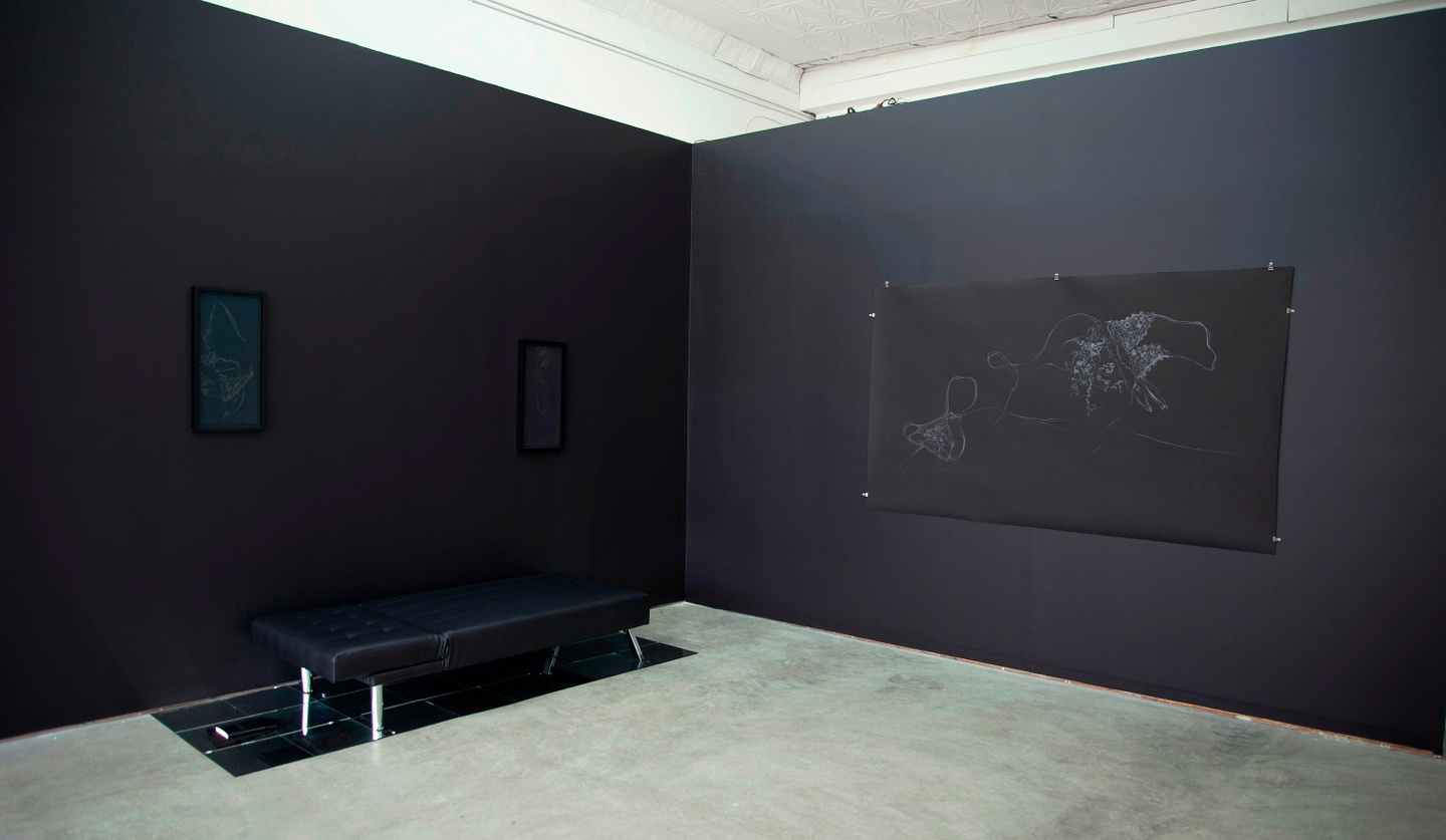 Works (white images against a black background) displayed in a gallery, whose walls are black. On the left hand wall are two tall rectangular frames/pieces (one of which is MS (Head)), placed far apart. In between them against the wall is a black bench, placed on a grid of tiled metallic/reflective panels. To the right is a larger piece (Night Watch) in landscape orientation. The floor is (likely) concrete, a light gray.