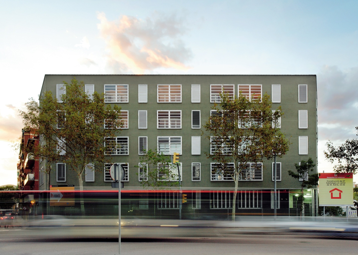 Five story, olive-green biulding with numerous rows of white windows with horizontal blinds.