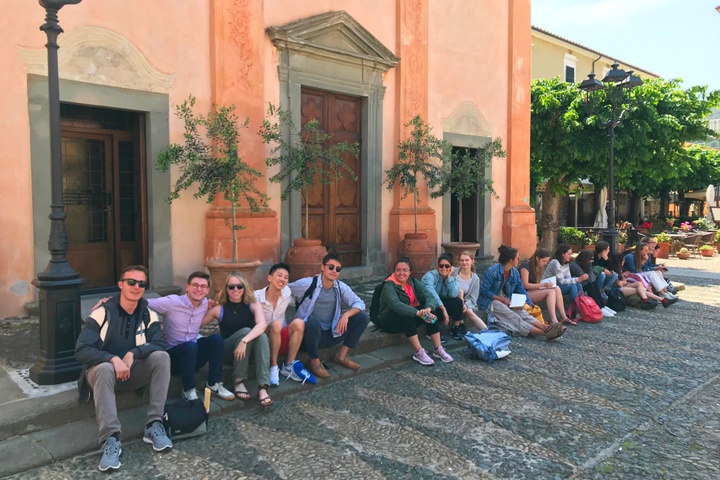 Students seted in front of a coral colored old church