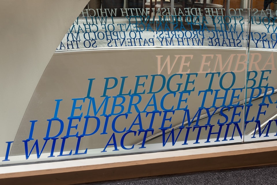 Detail photo of blue text vinyl on a glass half-wall with the hippocratic oath