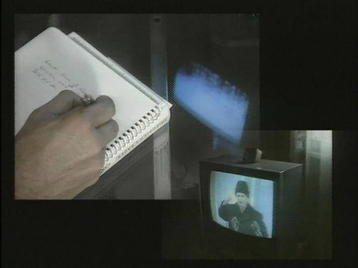 Hand writing in notebook, and person speaking on a television screen