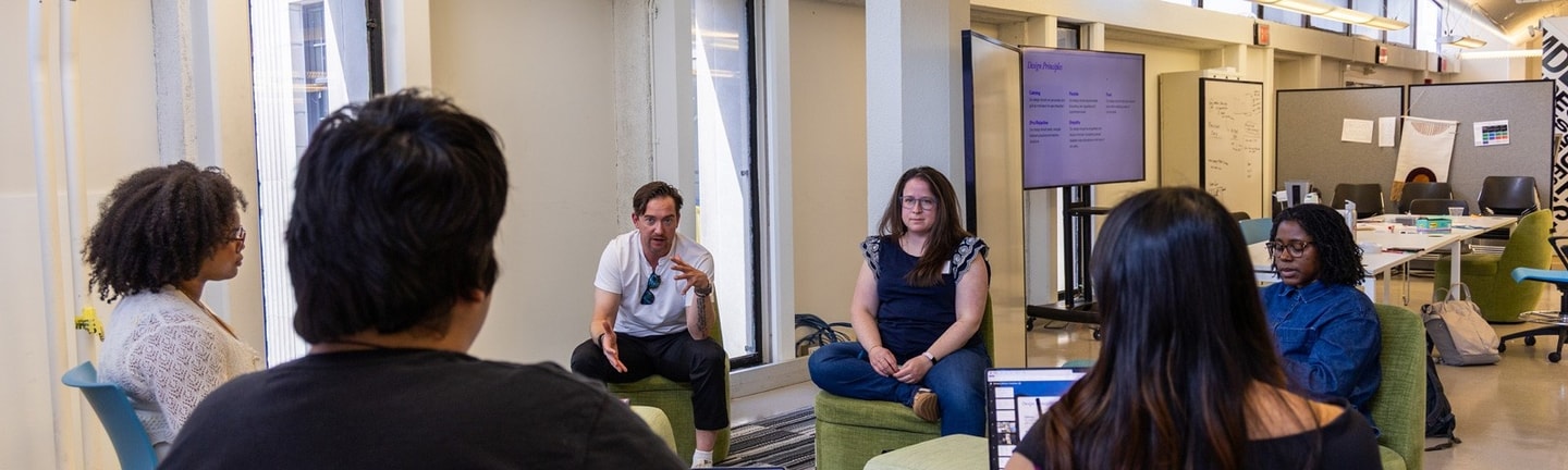 A group of people sit in chairs in a circle while discussion work