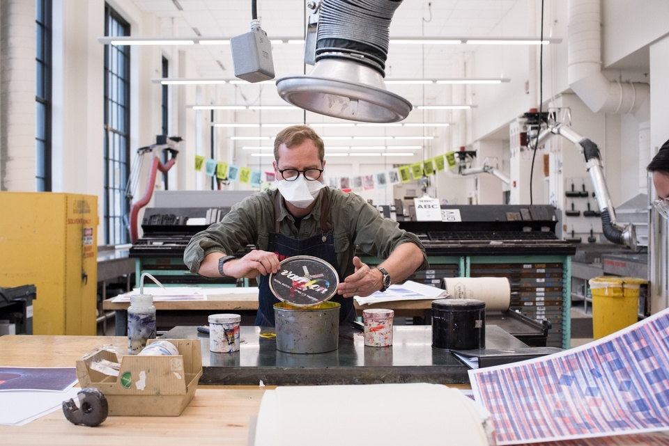 Person opens a large metal can of printmaking ink.