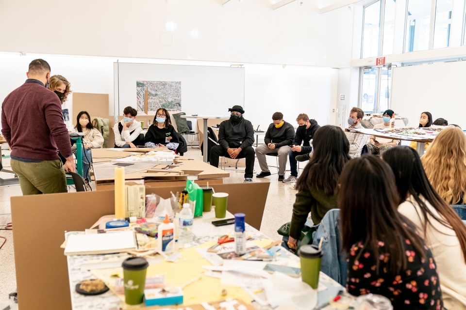 A room full of seated people around tables covered in crafting supplies.