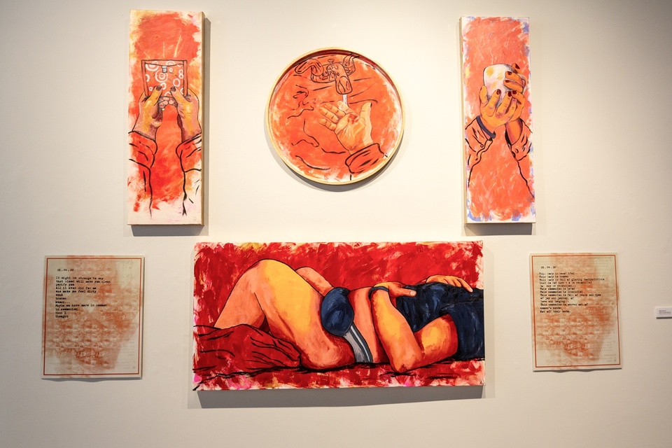 Gallery view of 6 paintings on a wall. The top 3 paintings are closeups of hands; first holding up a pad, second washing off blood, third is holding a mug. The bottom three images depict two paragraphs on either side and the middle depicts the side view of a figure laying down with a warm compress on their stomach.